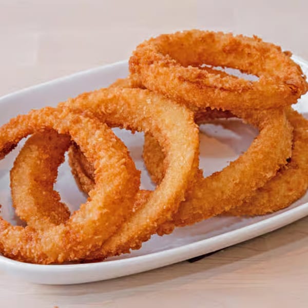 A white rectangular plate holds several golden-brown, crispy onion rings.