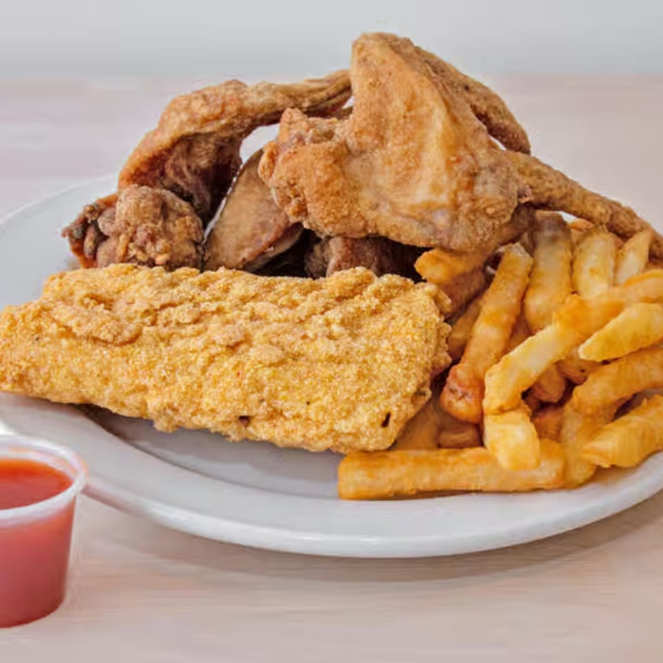 Crispy fried chicken wings, golden fish fillet, and french fries with a side of sauce.