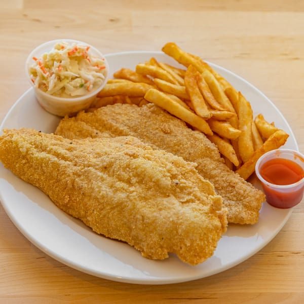 Two pieces of fried fish, french fries, coleslaw, and a cup of red sauce on a white plate.