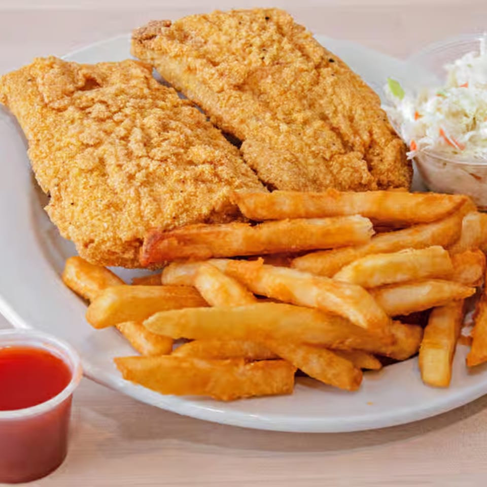 Two pieces of fried fish with a side of french fries, coleslaw, and a cup of red sauce.
